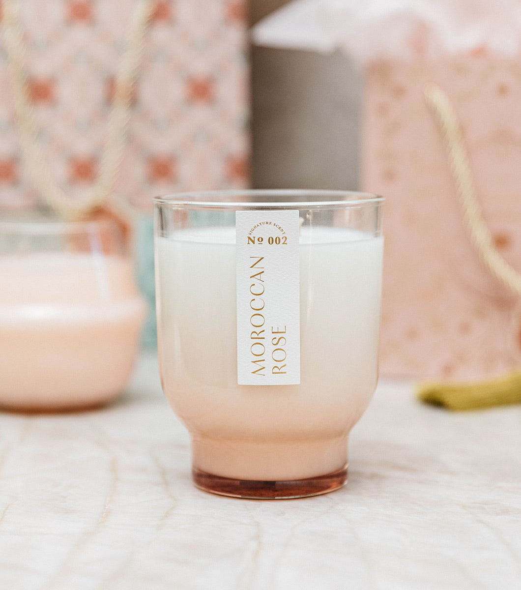 large pink moroccan rose scentd candle with moroccan rose collection gift bags in the background