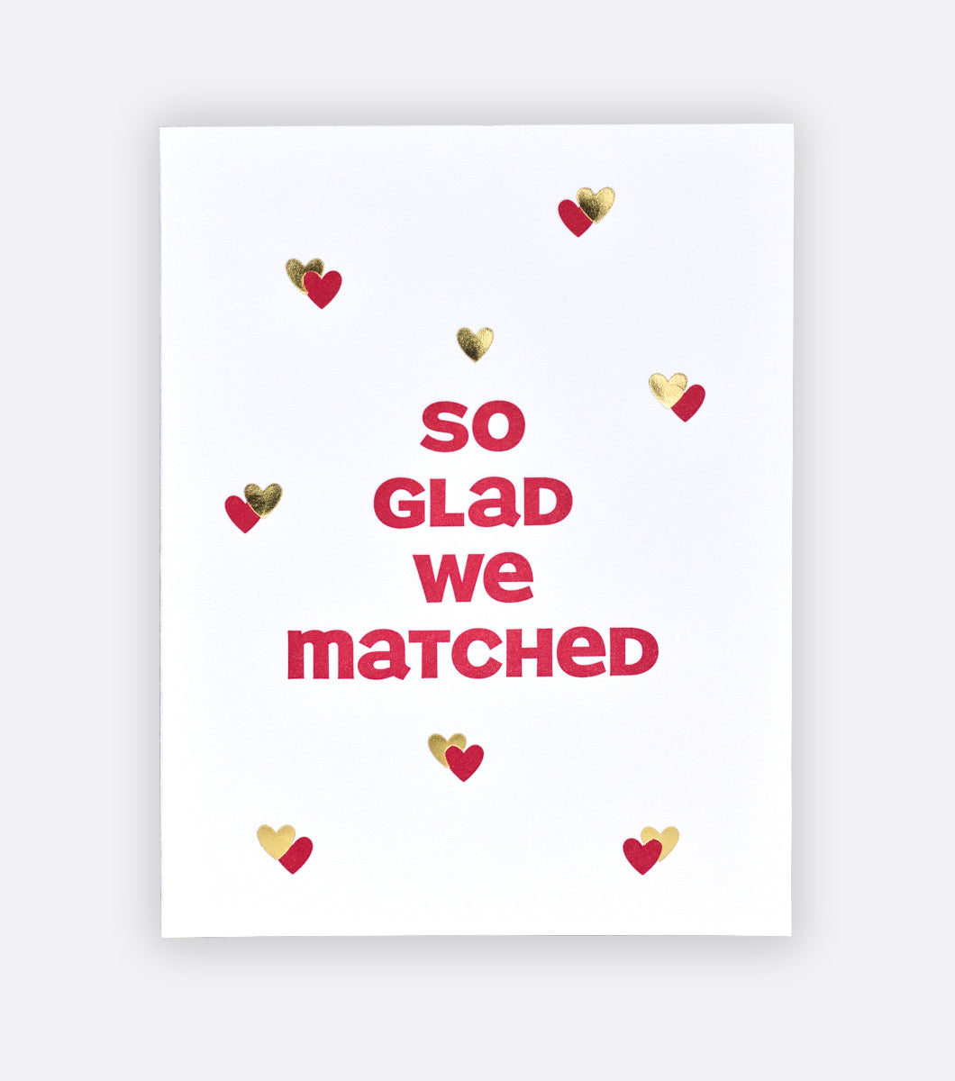 We Matched letterpress greeting card with light gray background front of greeting card features red and gold hearts and a message that says "so glad we matched"