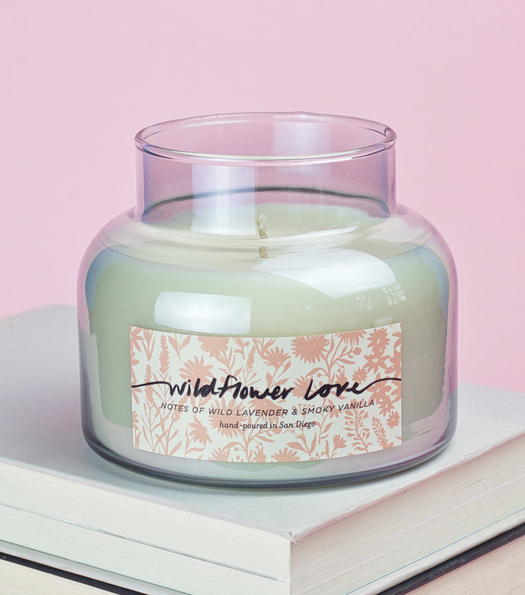 Elum designs wildflower love smoky glass candle on top of books with pink background