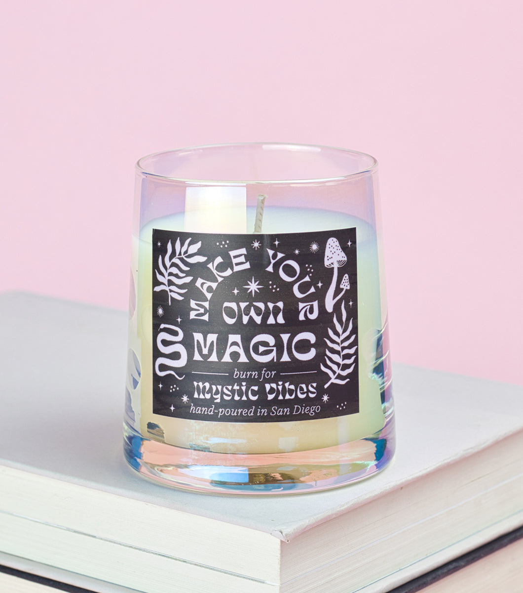 Elum Designs Mystic Scene Vibes Iridescent Glass Candle on stack of books with pink background 