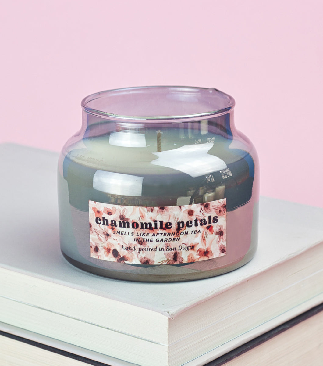 Elum Designs Washy Floral Small Smoky Glass Candle on stack of books with pink background