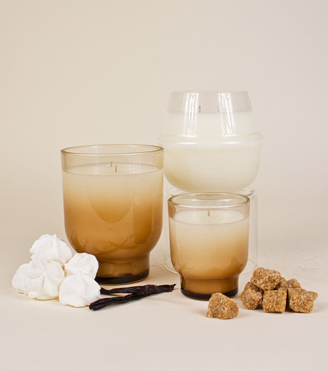 three classic vanilla scented candles of varying sizes and shapes pictured with vanilla beans, brown sugar cubes and fluffy meringue