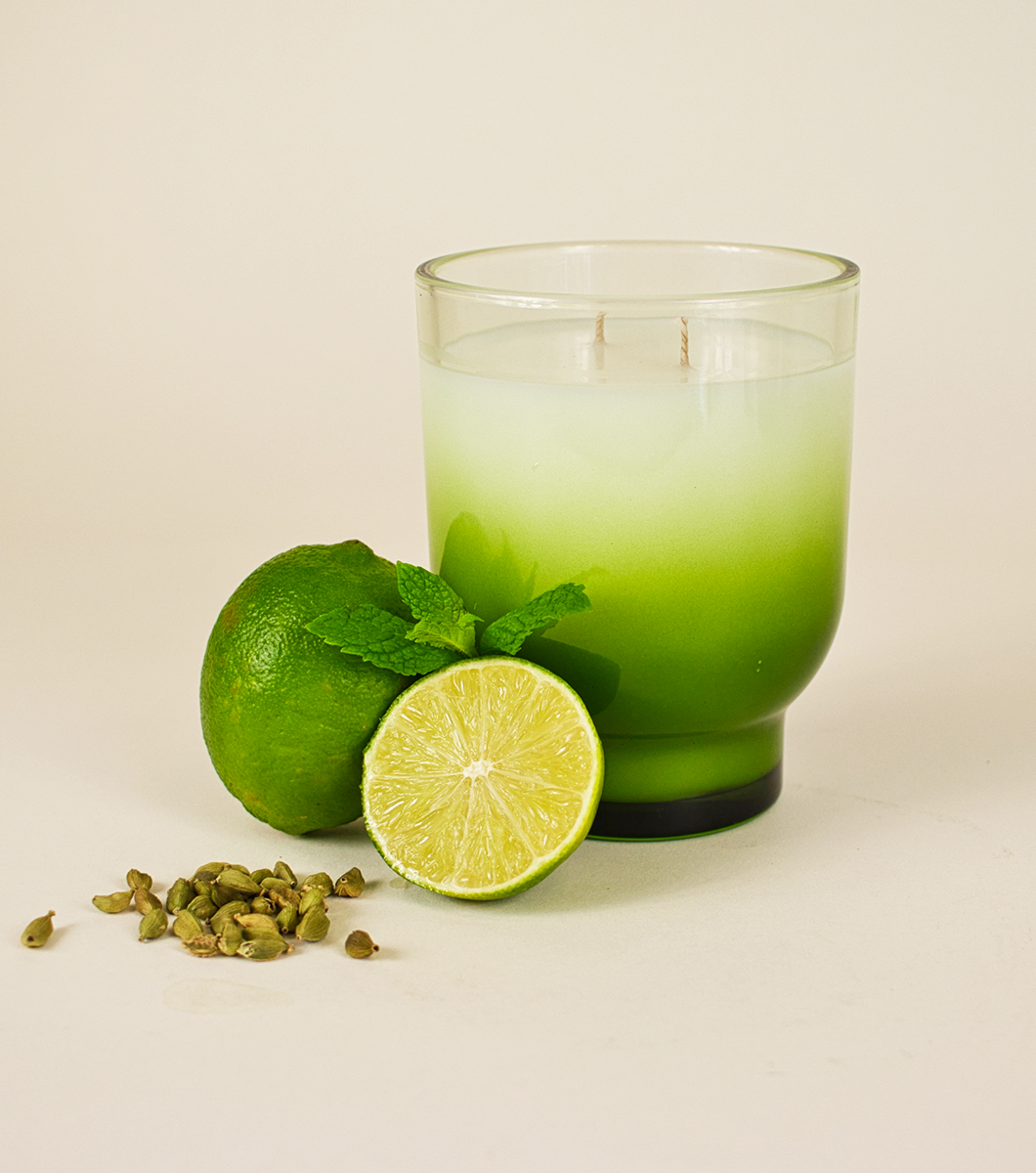 large green italian bergamot scented candle pictured with sliced limes, mint and cardamom