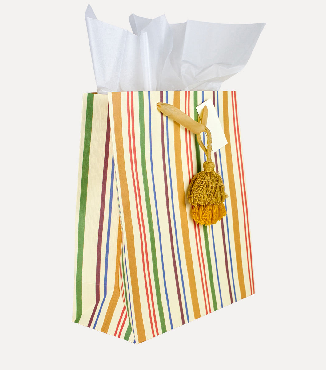 large yellow gift bag with multicolor vertical stripes and a hanging tassel with 3 included sheets of white tissue paper