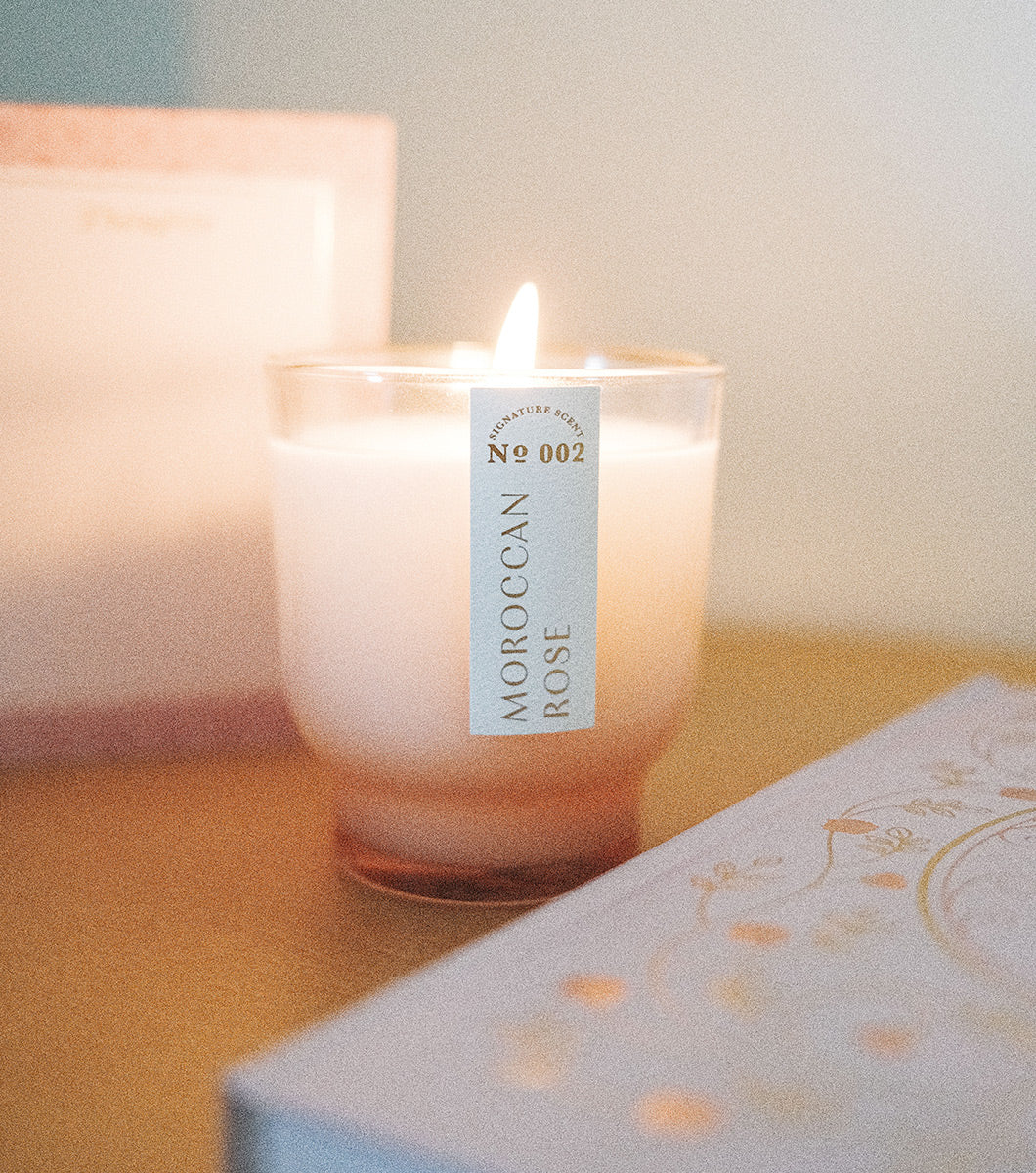 small moroccan rose scented candle lit next to a journal