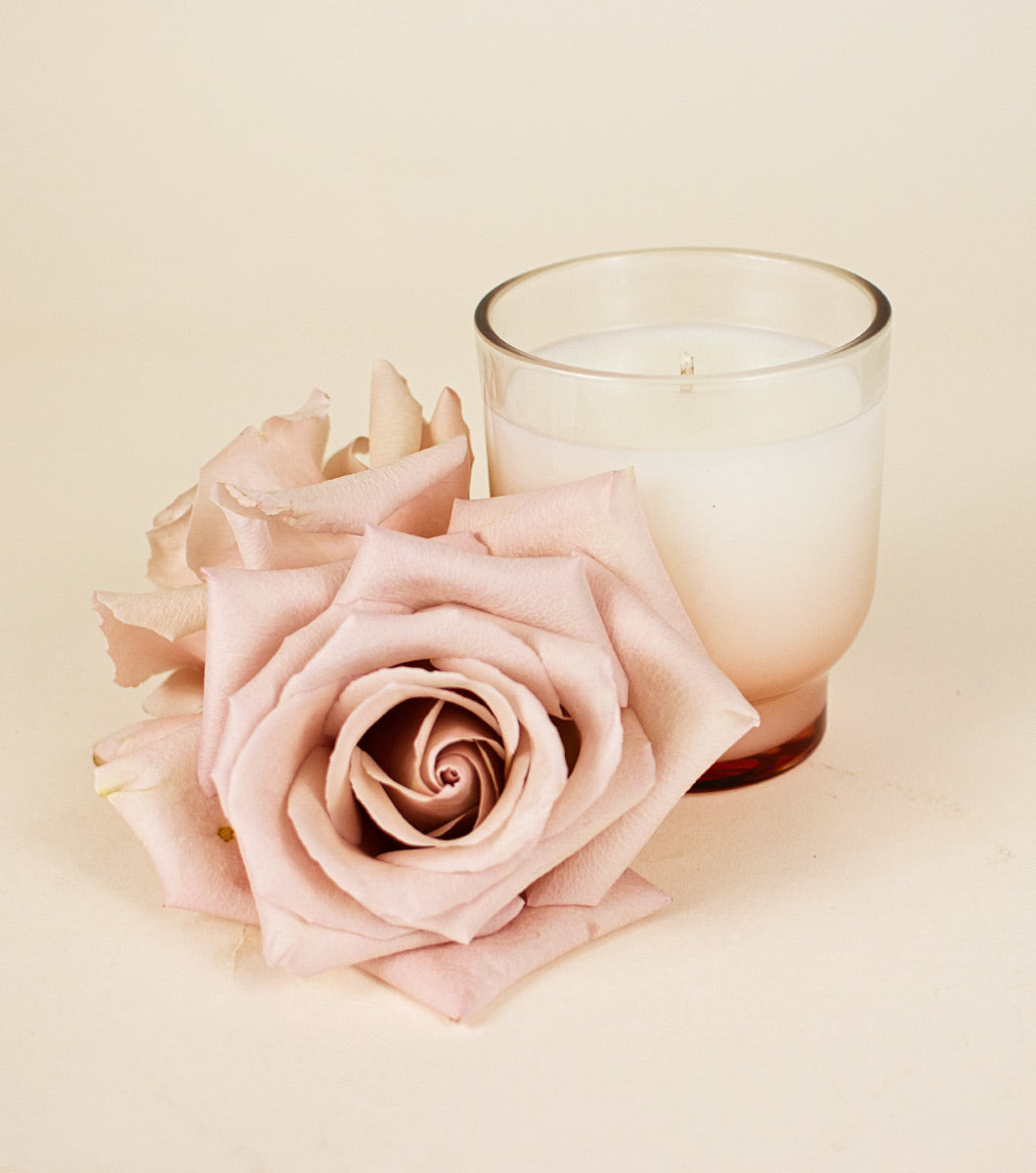 small moroccan rose scented candle with pink roses next to it