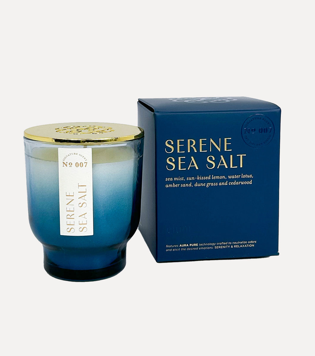 small blue serene sea salt scented candle pictured next to blue gift box