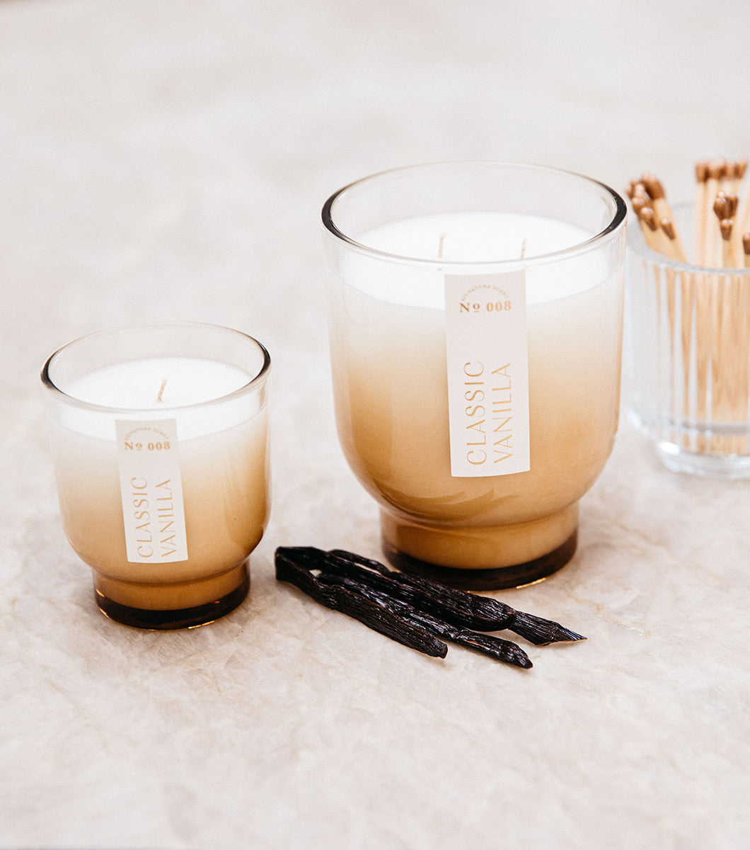 small and large vanilla scented candles pictured with some vanilla beans and matches