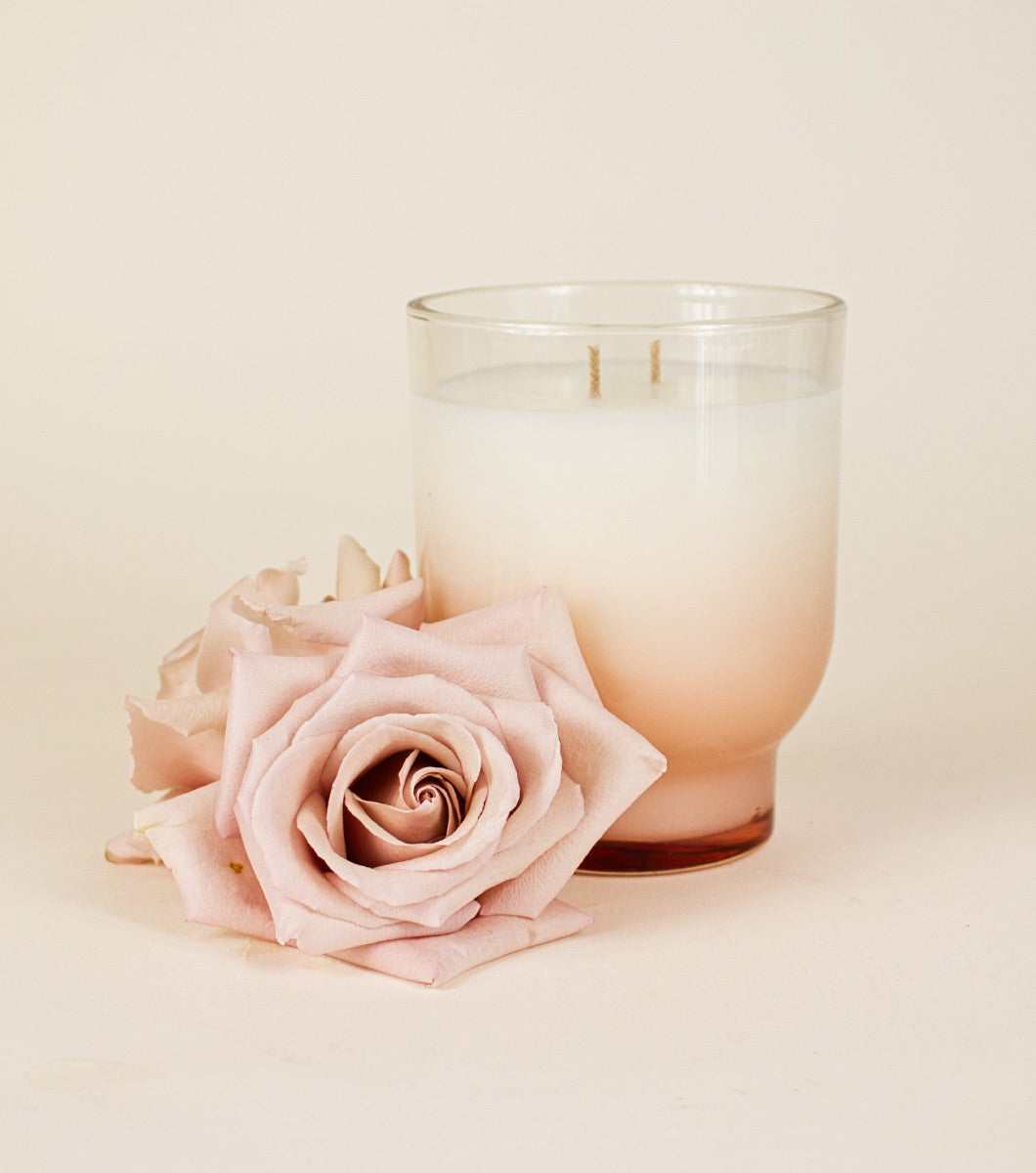 large pink moroccan rose scented candle pictured next to light pink roses