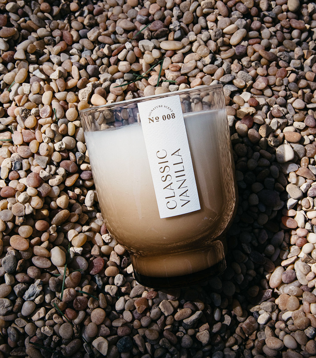 large classic vanilla scented candle pictured on a bed of gravel