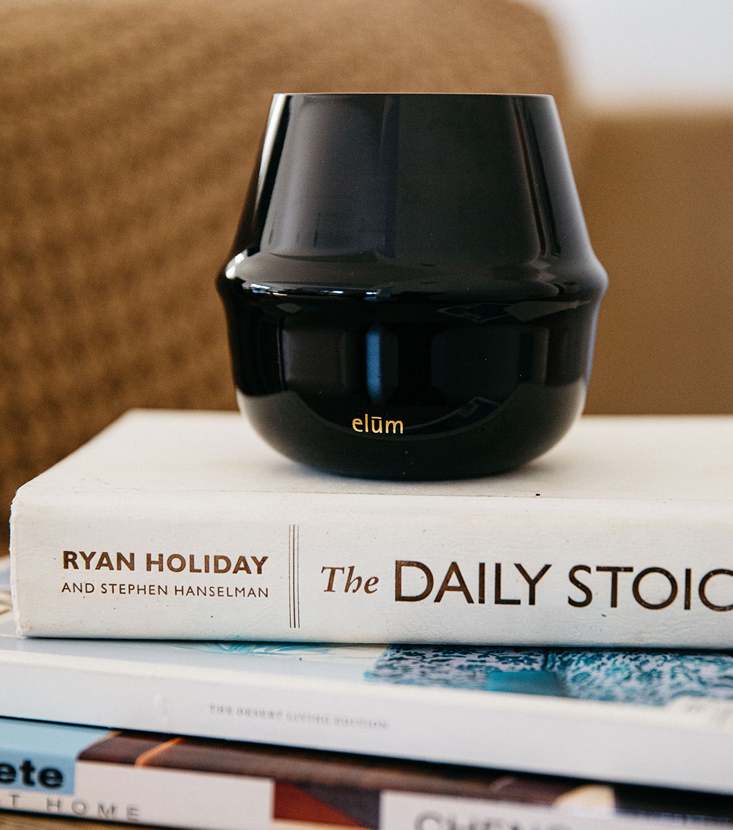 large black velvet sandalwood scented candle pictured on top of a stack of books