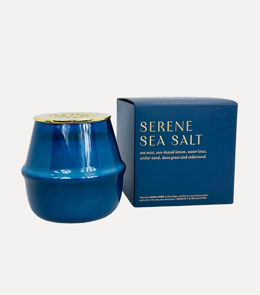 large round blue serene sea salt scented candle pictured next to included blue gift box