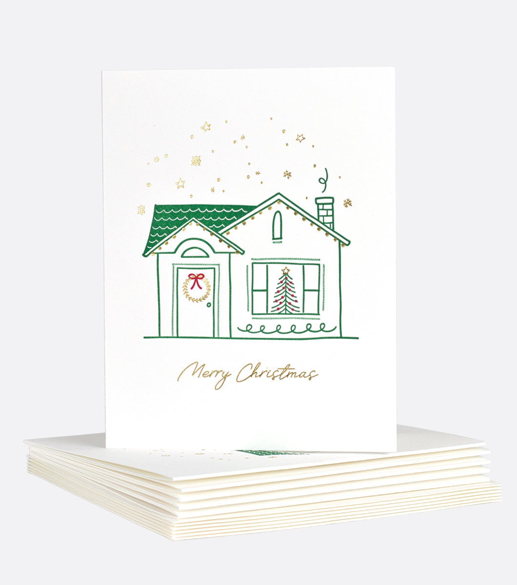 holiday greeting card with design that features a cozy house decorated for the holidays with gold foil accents and an inscription that says "merry christmas"