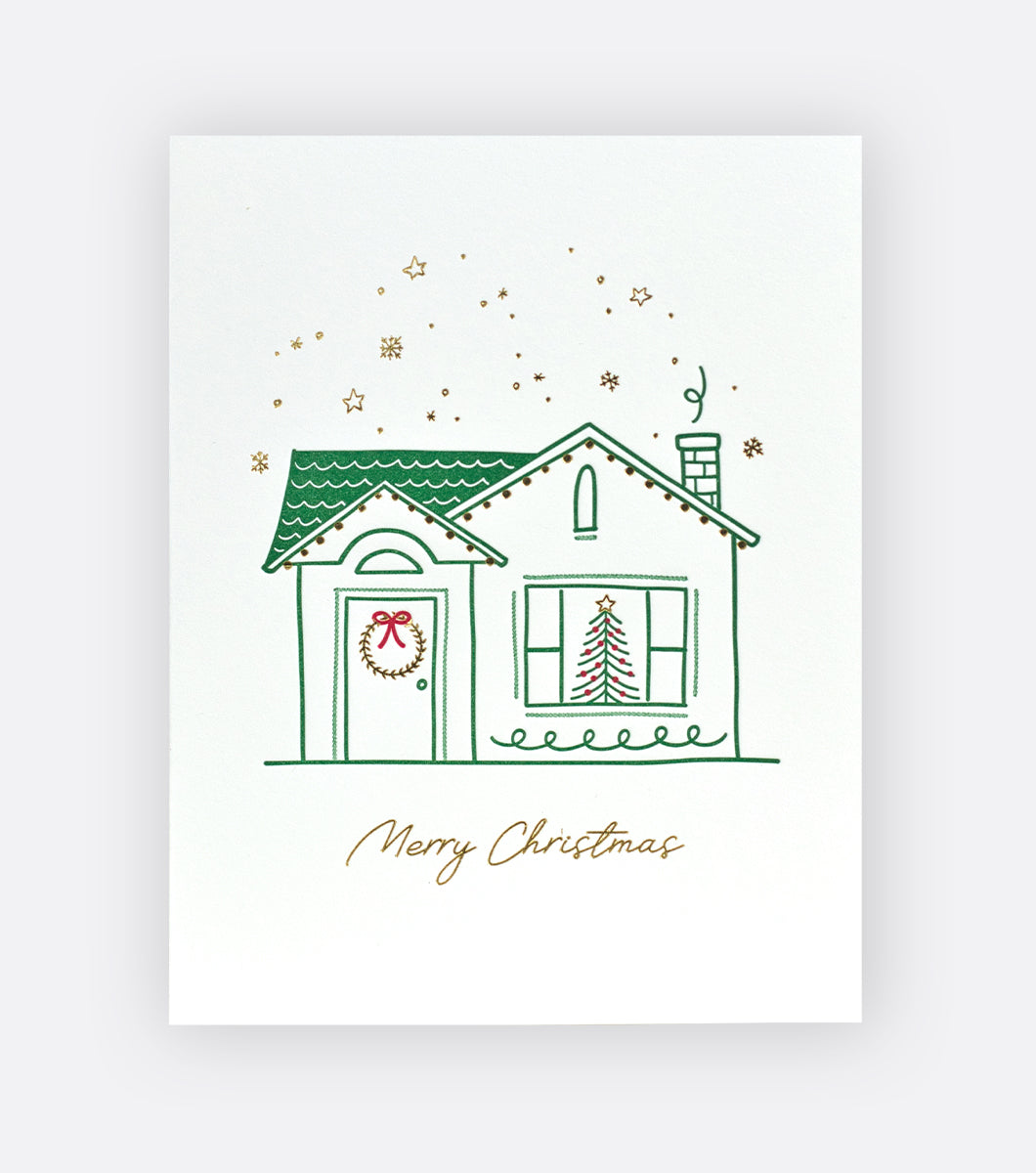 holiday greeting card with design that features a cozy house decorated for the holidays with gold foil accents and an inscription that says "merry christmas"