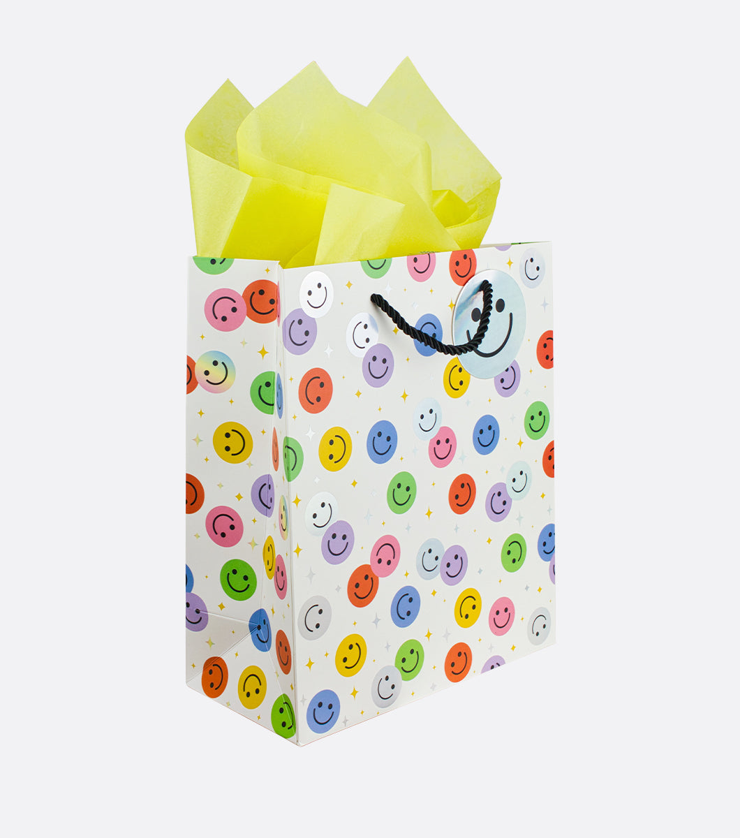 medium sized gift bag with colorful happy face design and holographic foil accents and yellow tissue paper