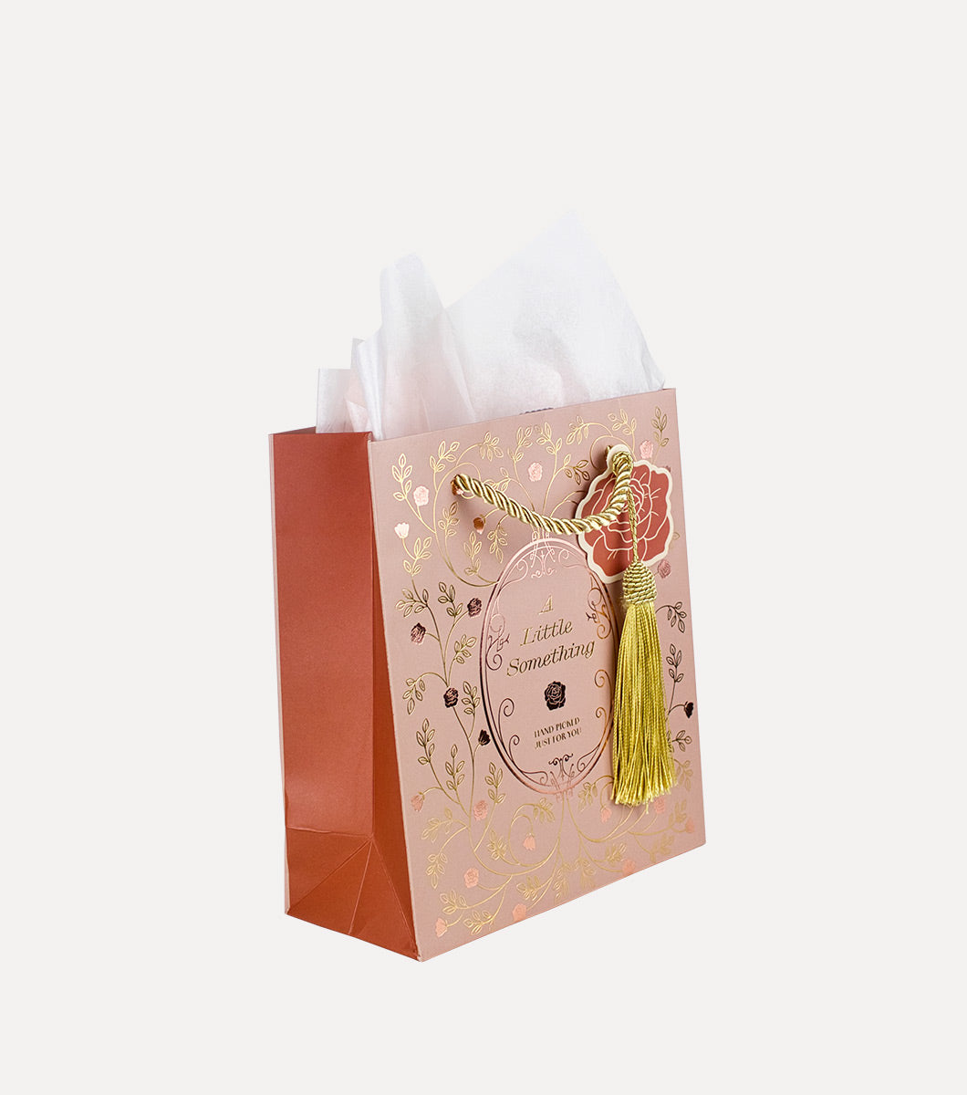small blush colored gift bag with a vintage rose design in rose gold and gold foil. Front of the gift bag says "A litlle something hand picked for you." Bag features gold hanging tassel, rose shaped hangtag and 3 sheets of included blush tissue paper
