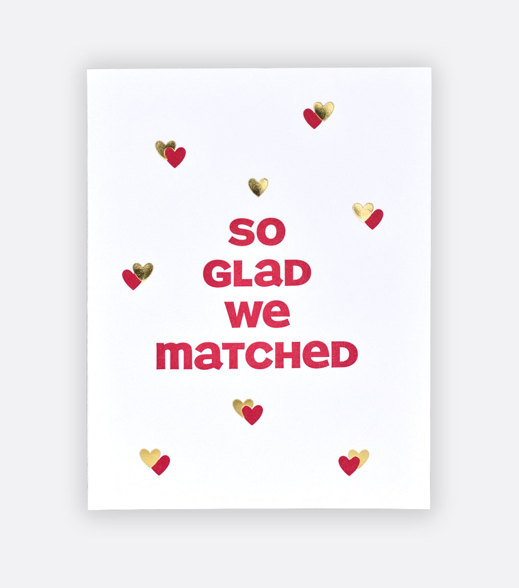 We Matched letterpress greeting card with light gray background front of greeting card features red and gold hearts and a message that says "so glad we matched" 