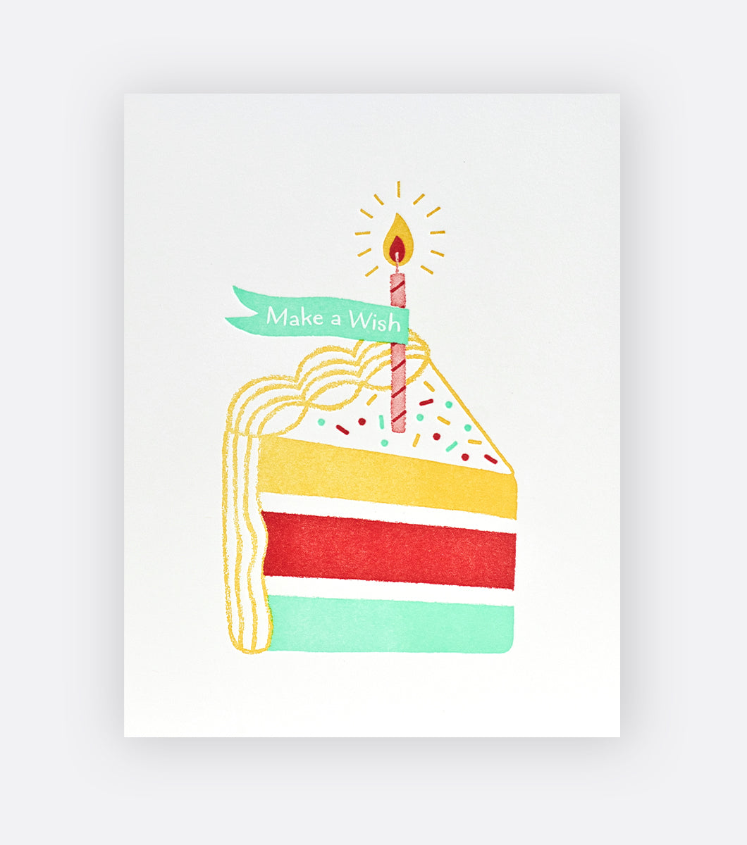 birthday greeting card with slice of multicolor birthday cake and a candle with a banner that says "make a wish" 